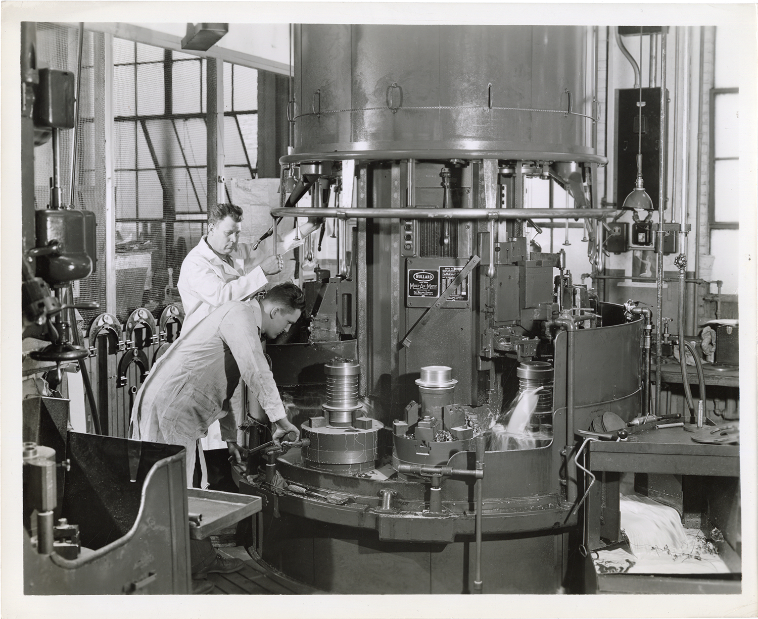 Workers operating Bullard machine for machining cylinders