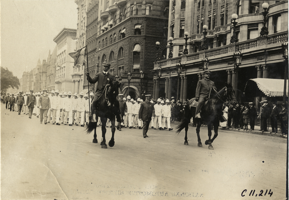 Men on horseback leading group of street cleaners, 1909 New York street