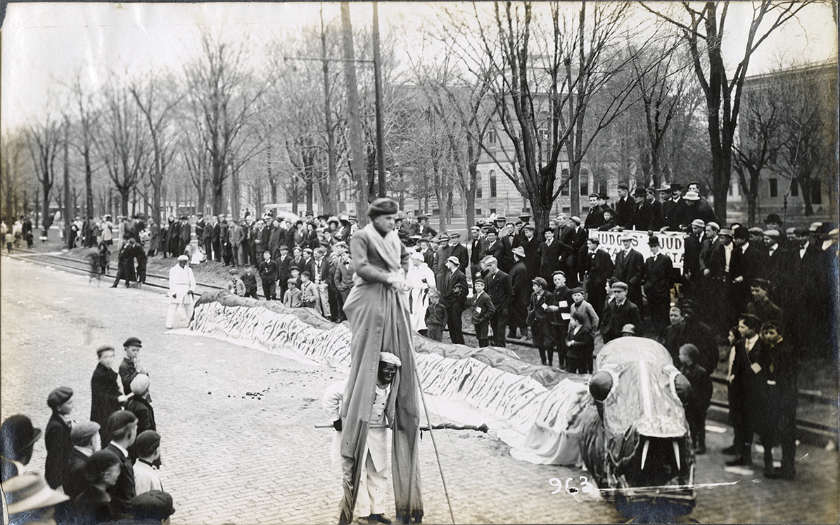 Stilt walker and dragon float in parade, University of Michigan